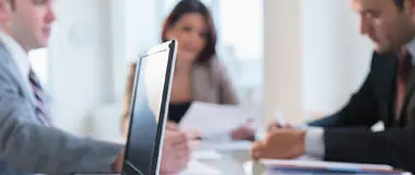 Business professionals in a meeting with a laptop in focus