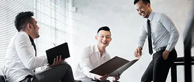 オフィスで話し合いながら笑顔を見せる3人のビジネスマン