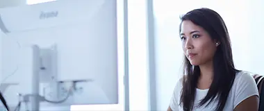 Focused young woman working at a desktop computer in an office