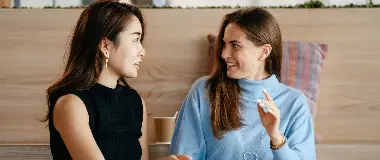 Two women sitting and smiling while talking together